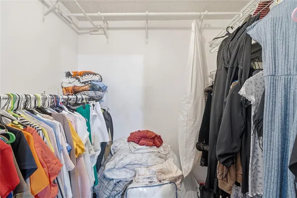 a view of walk in closet with clothes and shoes