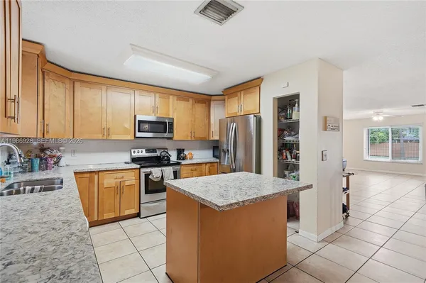 a kitchen with stainless steel appliances granite countertop a refrigerator stove microwave and sink