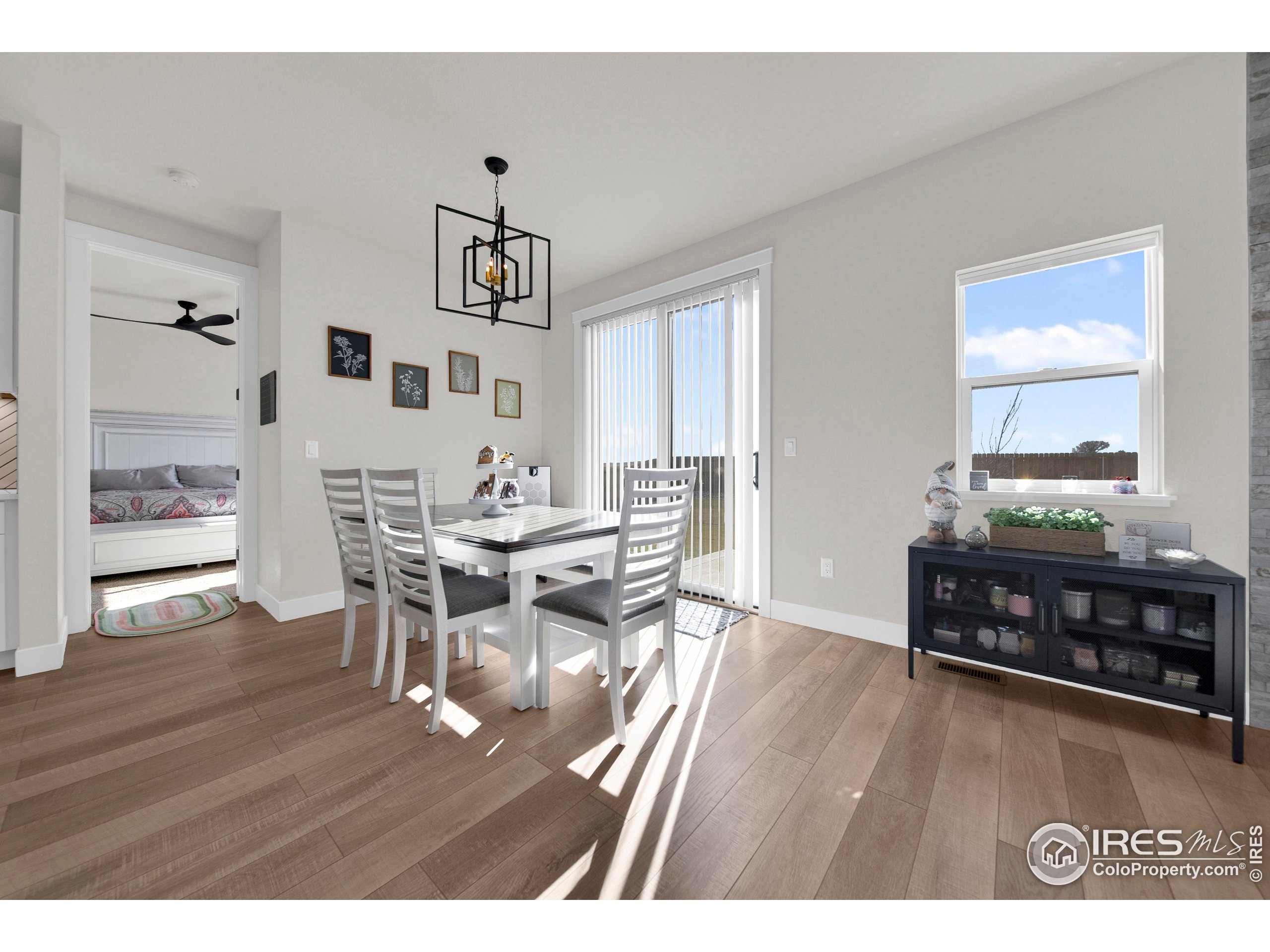 116 7th Avenue Wiggins, CO 80654 - Photo 16 of 42 a dining room with wooden floor a chandelier a wooden table and chairs