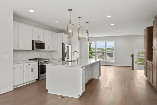 a large kitchen with stainless steel appliances granite countertop a stove and a wooden floors