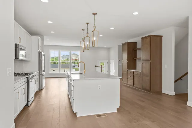 a kitchen with stainless steel appliances granite countertop white cabinets a stove a microwave and a refrigerator