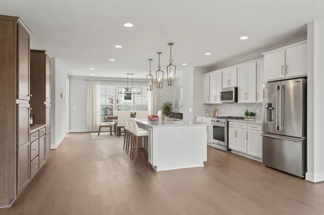 a large white kitchen with stainless steel appliances granite countertop a lot of cabinets and refrigerator