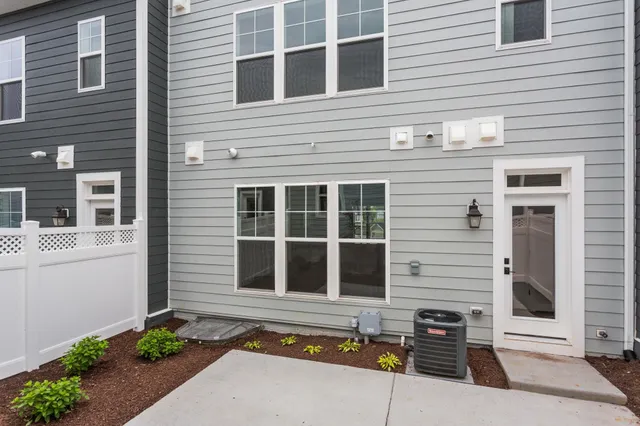 a view of a white house with a small yard and potted plants