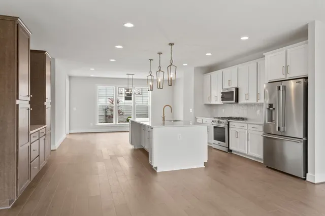 a large white kitchen with a refrigerator a stove a sink and a cabinets