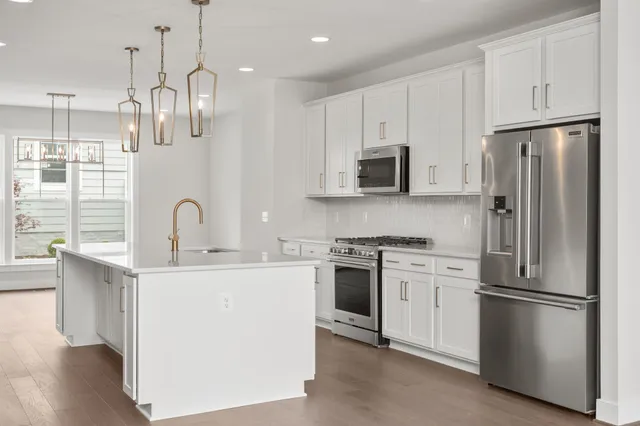 a kitchen with stainless steel appliances granite countertop a refrigerator a sink dishwasher a stove and a refrigerator