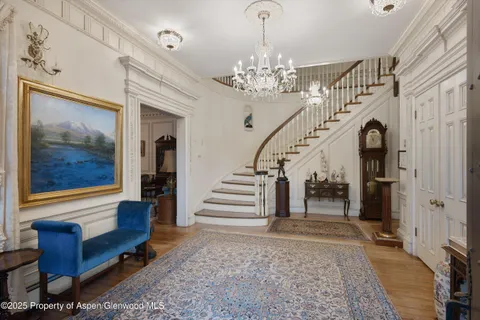 a view of a hallway with furniture and a chandelier
