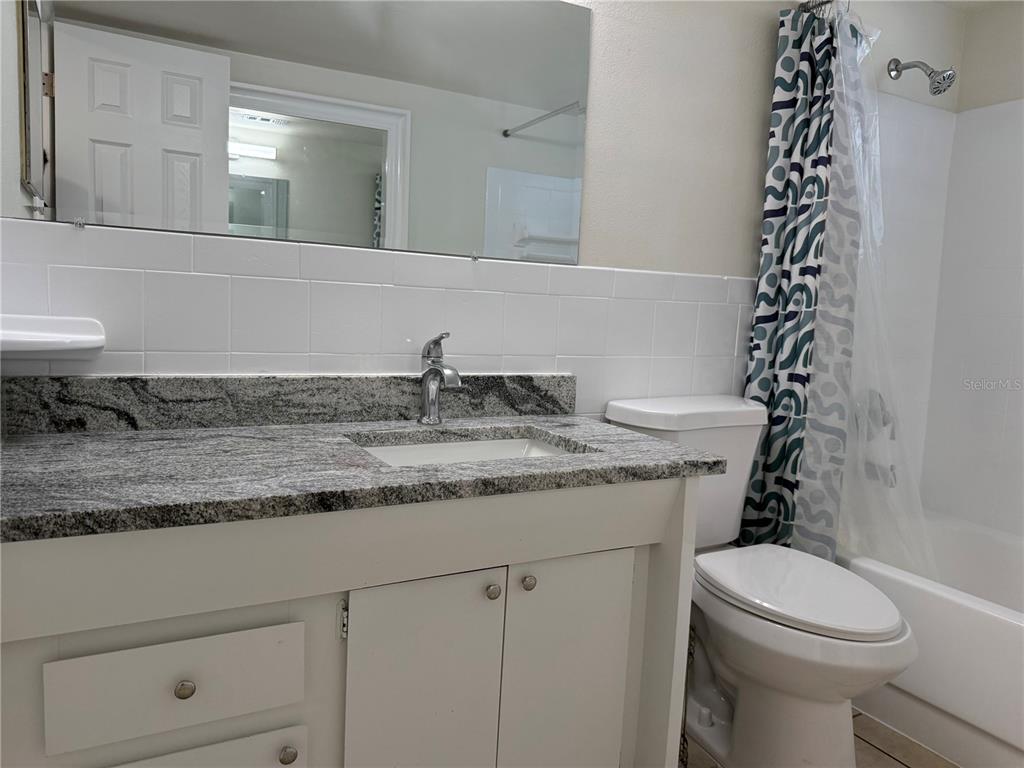 3625 Windham Drive Holiday, FL 34691 - Photo 24 of 28 a bathroom with a granite countertop toilet a sink and a mirror