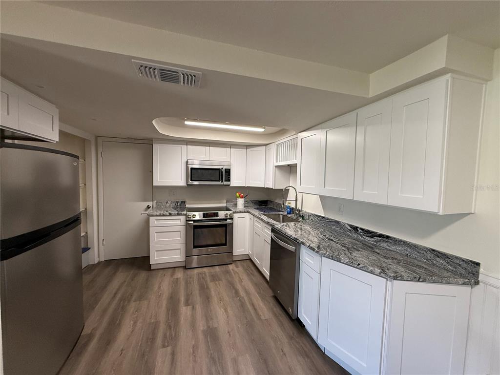 3625 Windham Drive Holiday, FL 34691 - Photo 9 of 28 a kitchen with stainless steel appliances granite countertop a stove a sink dishwasher a refrigerator white cabinets and wooden floor