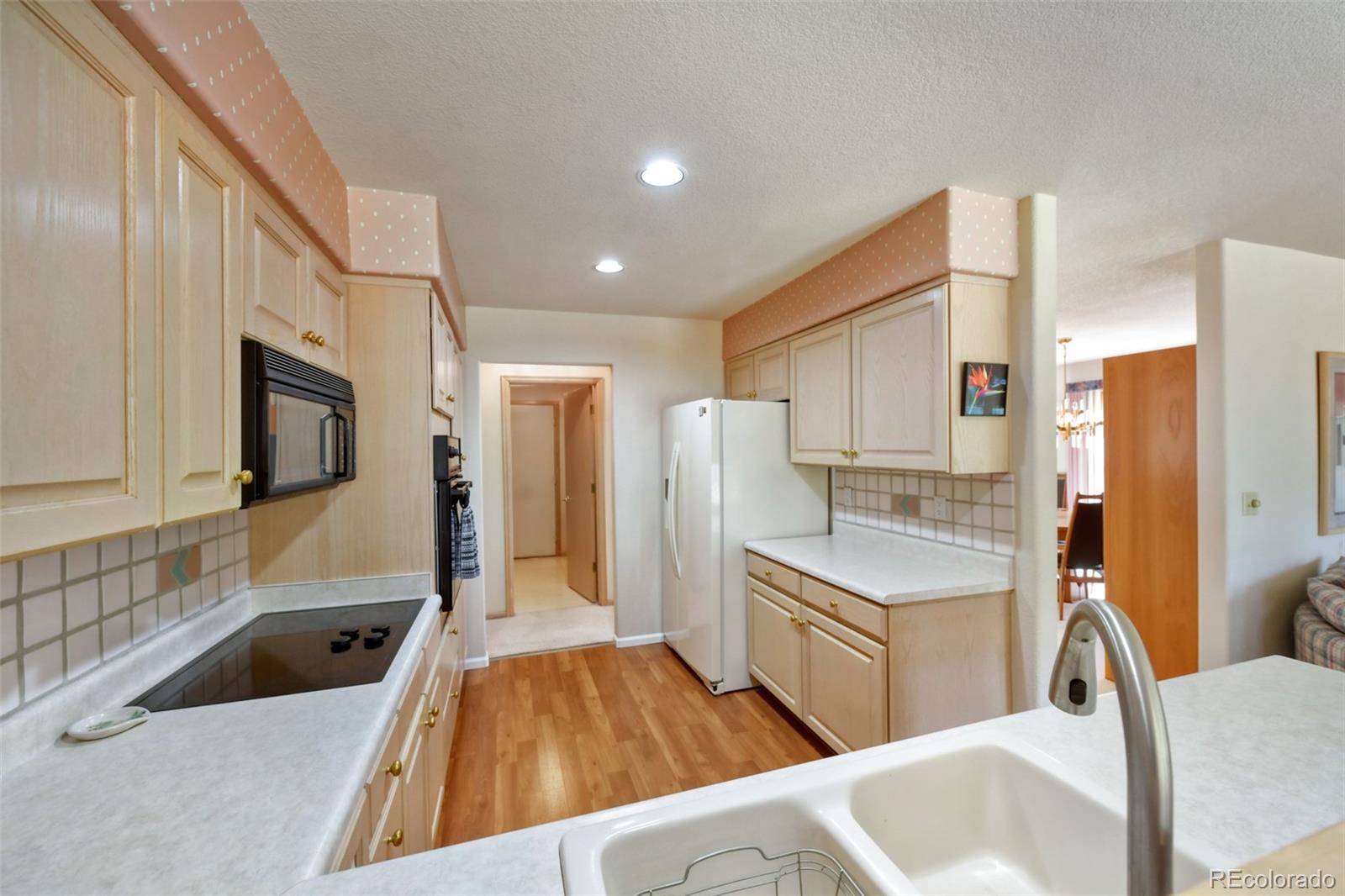 4823 Greenwich Place Highlands Ranch, CO 80130 - Photo 15 of 28 a kitchen with stainless steel appliances a sink a stove a refrigerator a cabinets and wooden floor