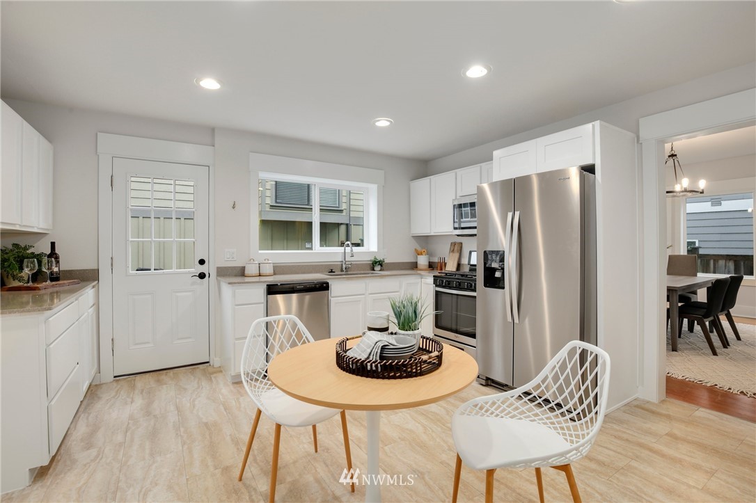 162 18th Avenue Seattle, WA 98122 - Photo 8 of 38 a kitchen with stainless steel appliances granite countertop a refrigerator a microwave a stove a dining table and chairs with wooden floor