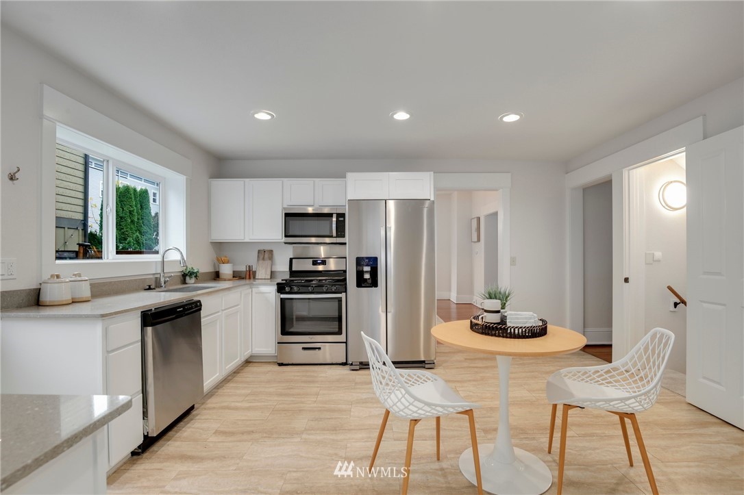 162 18th Avenue Seattle, WA 98122 - Photo 10 of 38 a kitchen with stainless steel appliances kitchen island granite countertop a dining table chairs and a refrigerator
