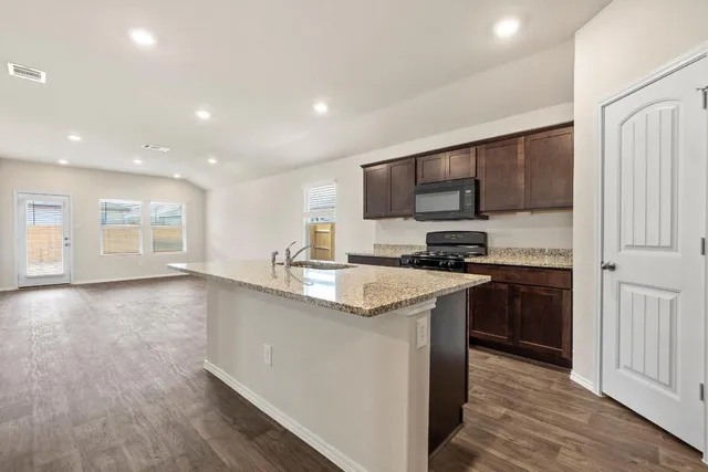 a kitchen with stainless steel appliances granite countertop a stove a sink and a refrigerator