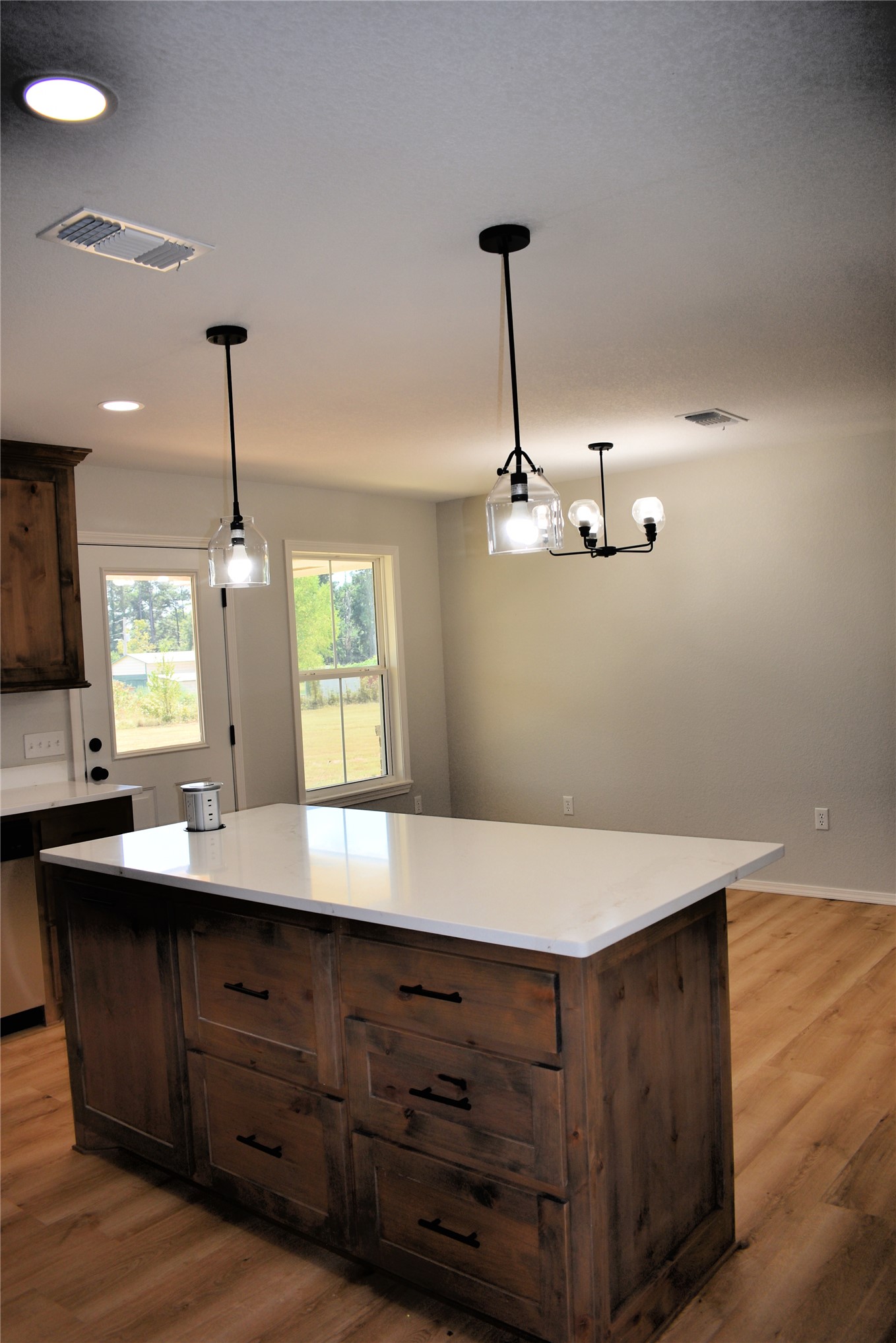 2915 East 2090 Road Hugo, OK 74743 - Photo 9 of 27 Kitchen island with a light-toned countertop, wood-finish flooring, recessed lighting, and modern pendant light fixtures