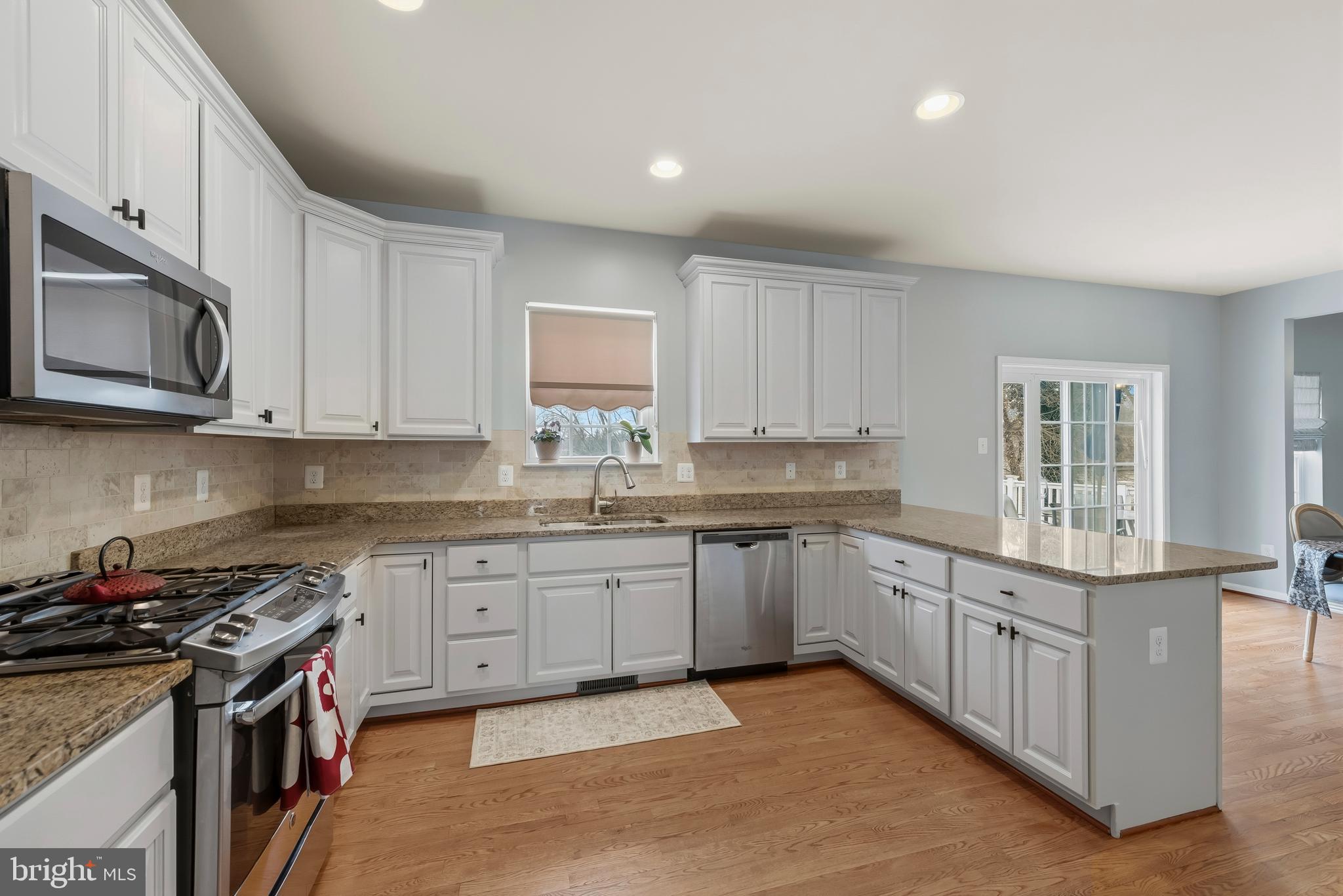 3007 Bender Ridge Court Baltimore, MD 21234 - Photo 9 of 39 a kitchen with stainless steel appliances granite countertop a stove top oven a sink dishwasher and a microwave oven with white cabinets