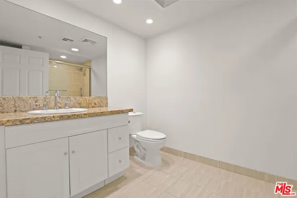 a bathroom with a granite countertop sink a toilet and a mirror