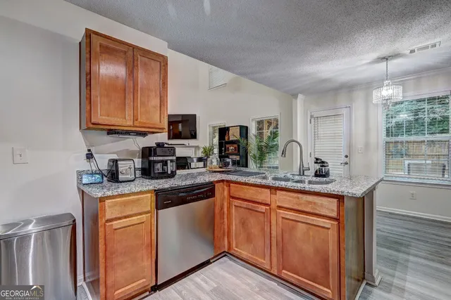 a kitchen with granite countertop cabinets stainless steel appliances a sink and wooden floor