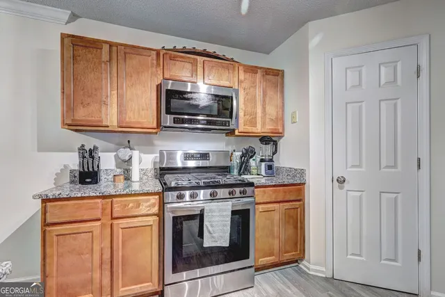 a kitchen with granite countertop a stove top oven microwave and cabinets