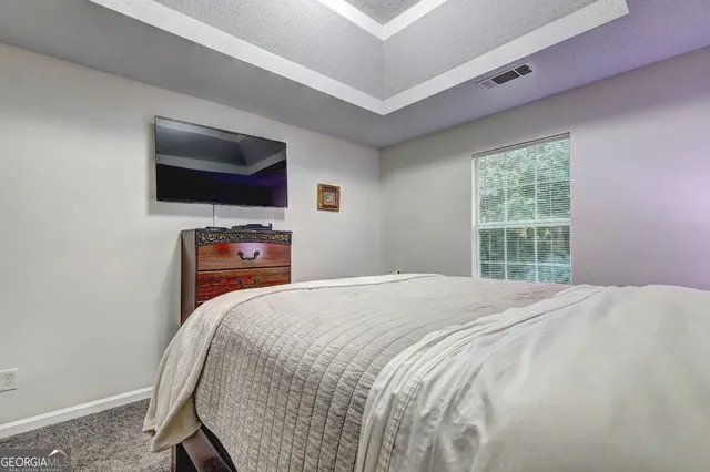 a bedroom with a bed and a lamp on dresser