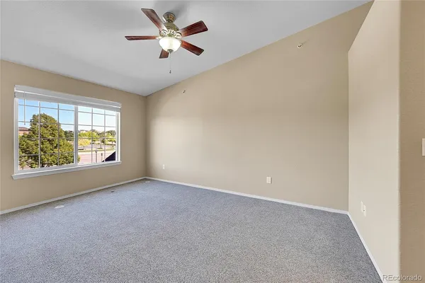 an empty room with windows and fan