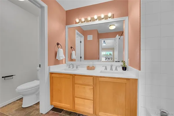 a bathroom with a granite countertop sink a toilet and a mirror