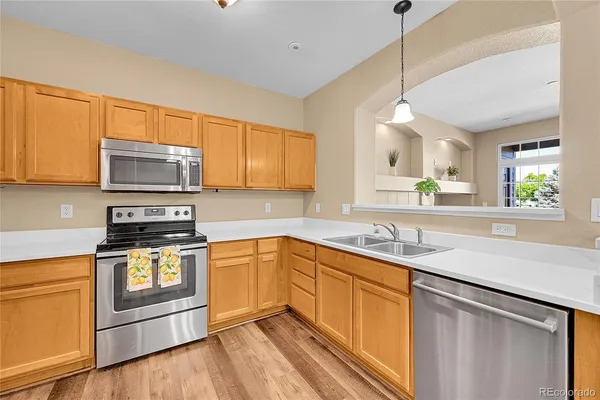 a kitchen with stainless steel appliances granite countertop a sink a stove and a wooden floors