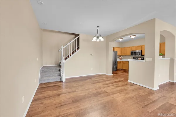 a view of a hallway with wooden floor staircase and kitchen view