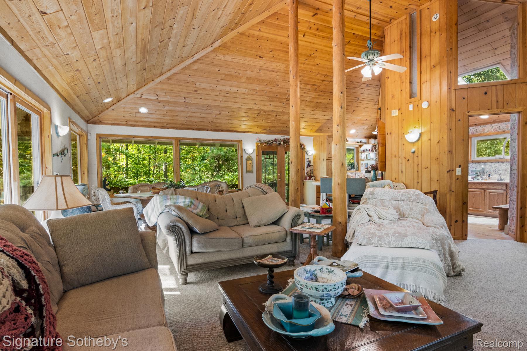 11436 Lakeview Road Northeast Kalkaska, MI 49646 - Photo 7 of 29 Carpeted living area with high vaulted ceiling, wood ceiling, wood walls, and a ceiling fan
