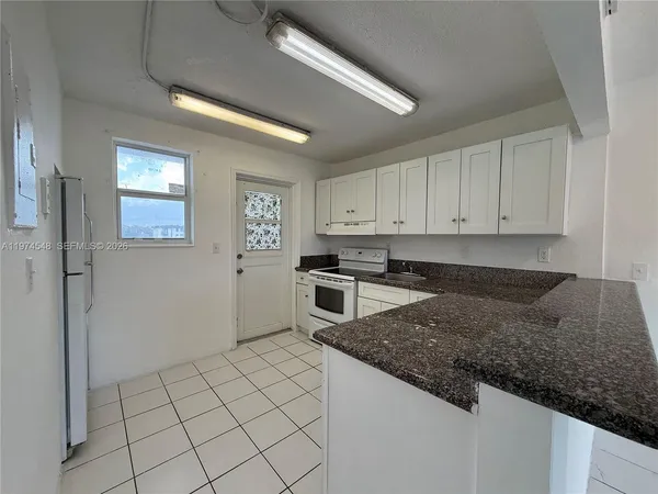 a kitchen with granite countertop white cabinets and stainless steel appliances