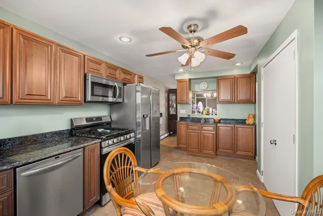 a kitchen with stainless steel appliances granite countertop a sink a stove a refrigerator cabinets a dining table and chairs with wooden floor