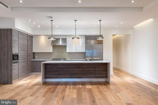 a large kitchen with kitchen island a counter space a sink stainless steel appliances and cabinets