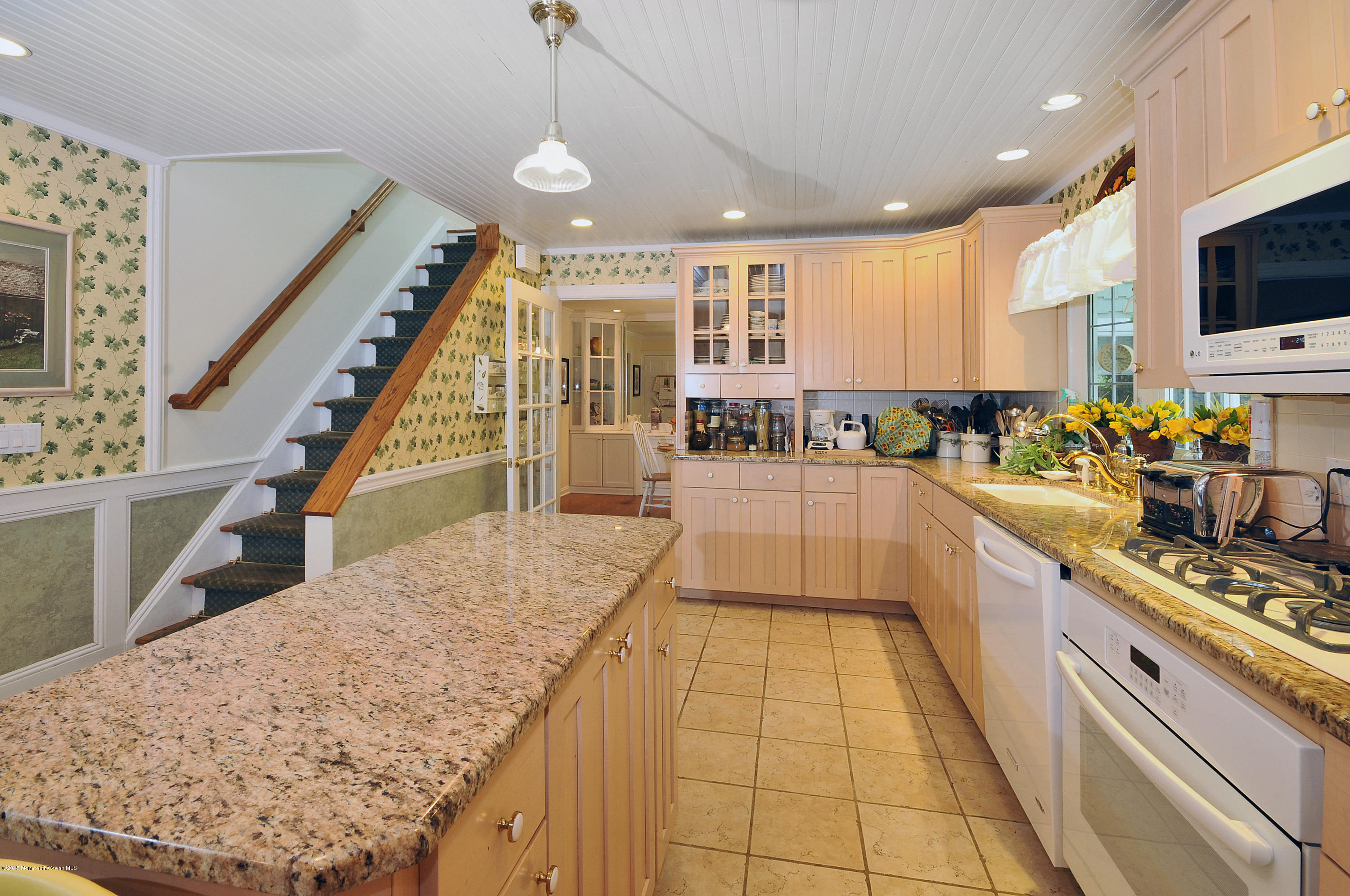 57 Heyers Mill Road Colts Neck, NJ 07722 - Photo 32 of 35 a large kitchen with stainless steel appliances kitchen island granite countertop a large counter top a stove a chimney a sink and a living room view