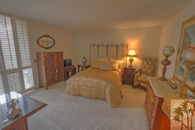 72025 Petunia Way Rancho Mirage, CA 92270 - Photo 11 of 18 a spacious bedroom with a bed a dresser and a chandelier