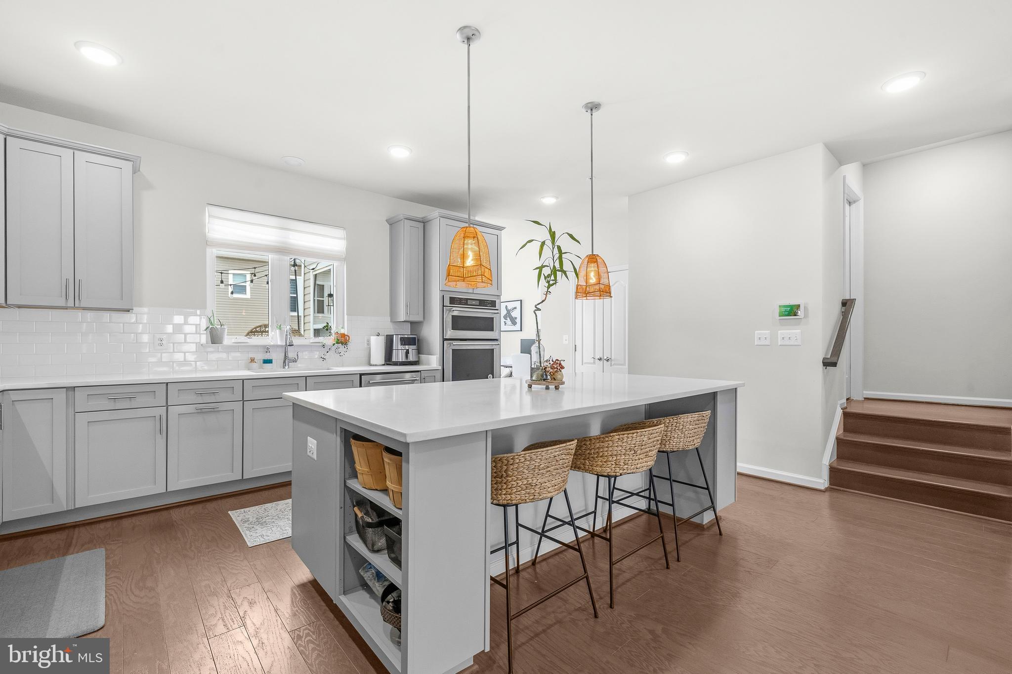 7715 Cresap Lane Hanover, MD 21076 - Photo 9 of 42 a kitchen with kitchen island a white counter top space a sink a stove and a wooden floor
