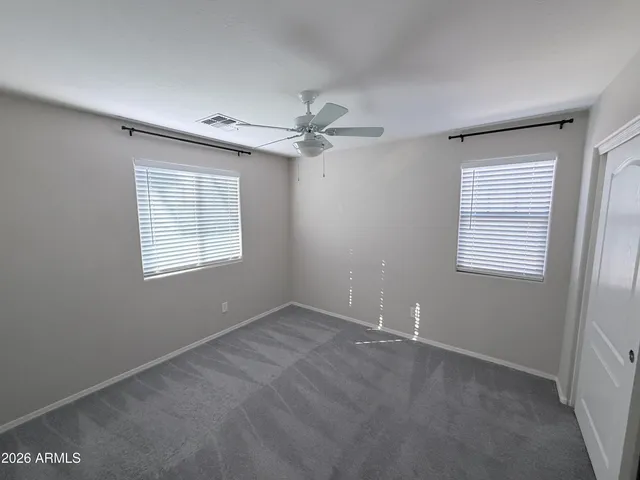 an empty room with windows and fan