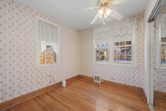 a view of empty room with wooden floor and fan