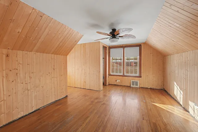 an empty room with wooden floor closet and windows