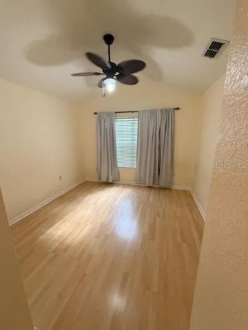 an empty room with a ceiling fan and wooden floor