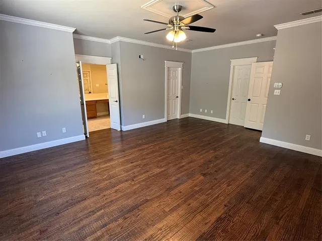a view of an empty room with wooden floor and a ceiling fan