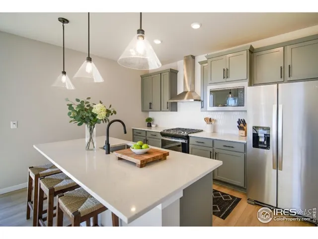 a kitchen with kitchen island a stove a refrigerator a sink a dining table and chairs