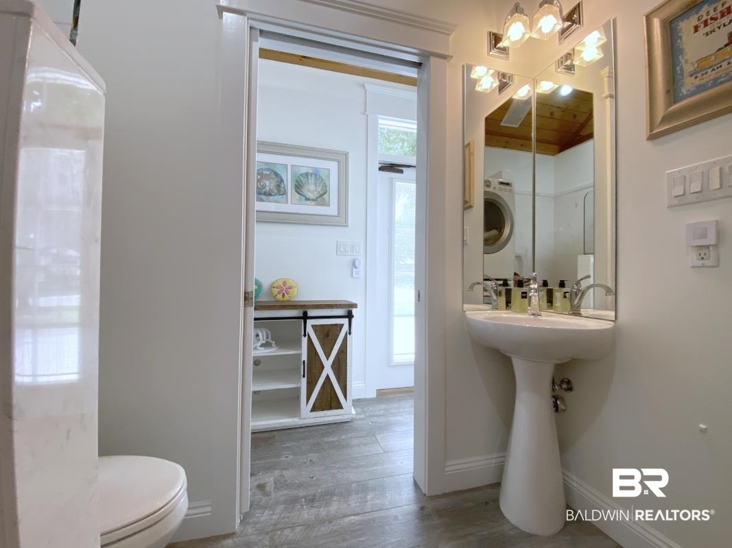 28888 Canal Road, Unit 77 Orange Beach, AL 36561 - Photo 8 of 23 Pedestal sink with chrome fixtures and a segmented mirror with vanity lighting