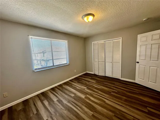 an empty room with wooden floor closet and windows