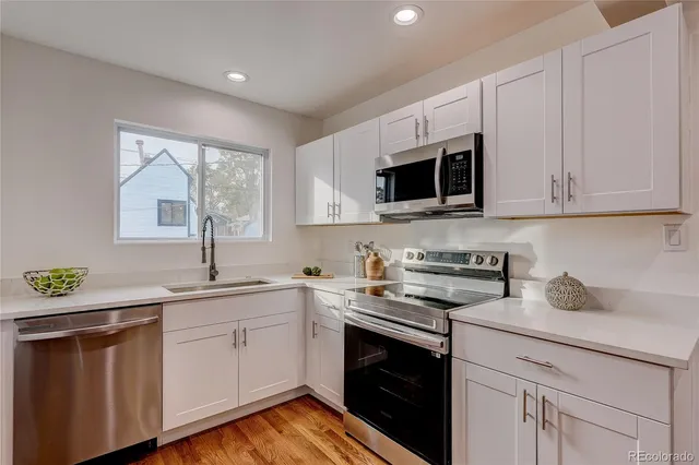 a kitchen with granite countertop white cabinets white stainless steel appliances and sink