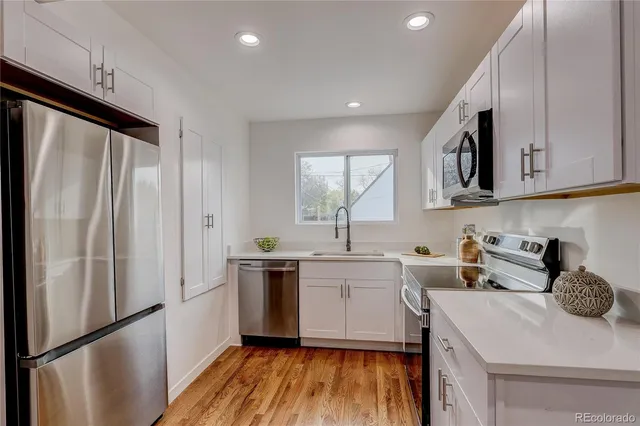 a kitchen with a sink a refrigerator a window and cabinets