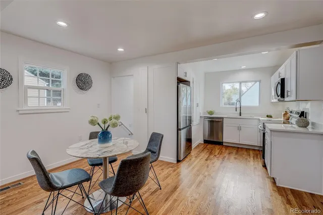 a kitchen with stainless steel appliances kitchen island granite countertop a dining table chairs and sink