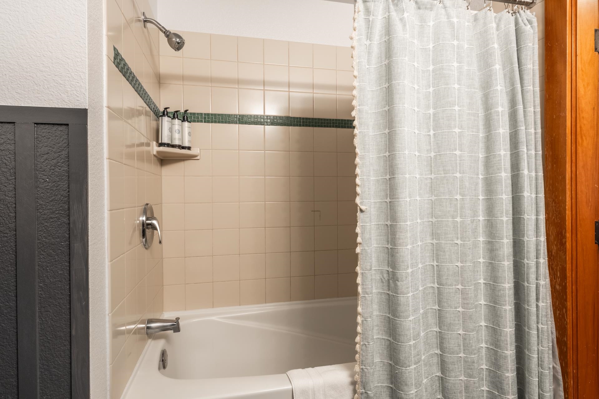 6201 Minaret Road, Unit 2221 Mammoth Lakes, CA 93546 - Photo 14 of 32 Bathtub and shower combination featuring beige wall tiles with a green accent stripe