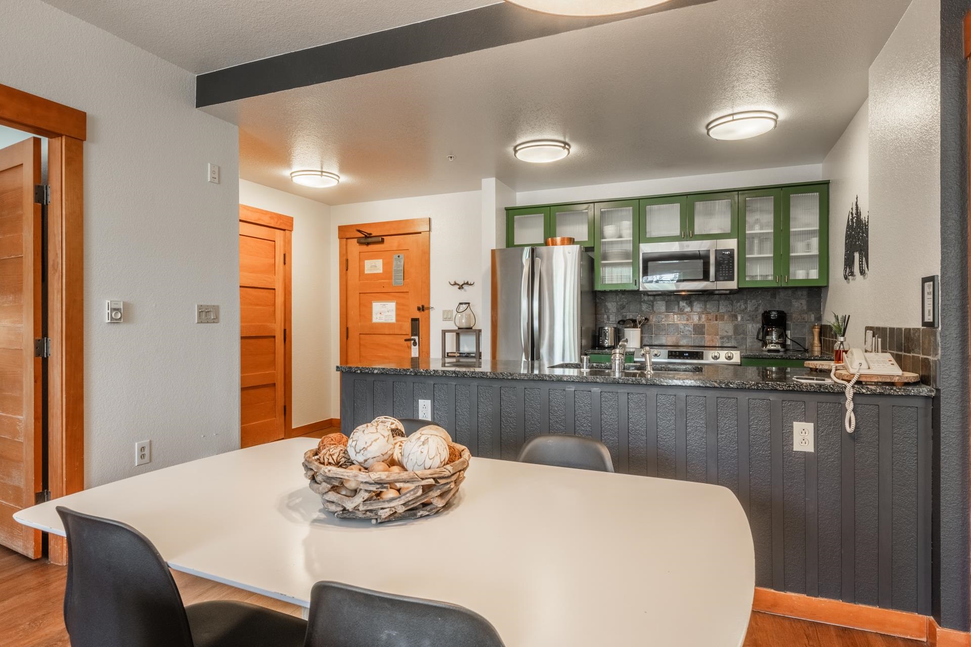 6201 Minaret Road, Unit 2221 Mammoth Lakes, CA 93546 - Photo 16 of 32 Kitchen featuring stainless steel appliances, green upper cabinetry with glass inserts, and a dark stone-finish countertop