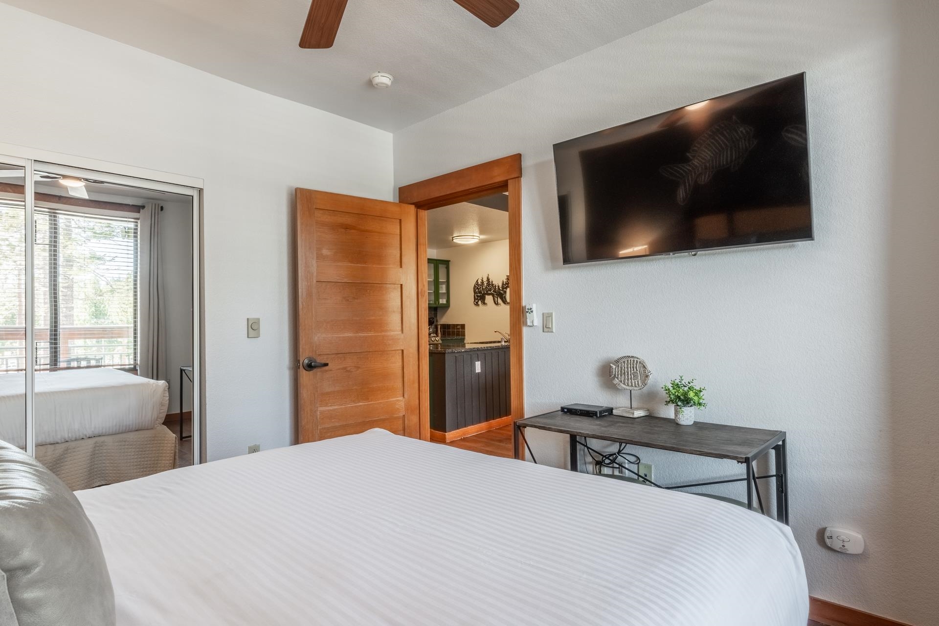 6201 Minaret Road, Unit 2221 Mammoth Lakes, CA 93546 - Photo 23 of 32 Bedroom featuring a ceiling fan, wood-finish door, wall-mounted television, and a sliding mirrored closet door