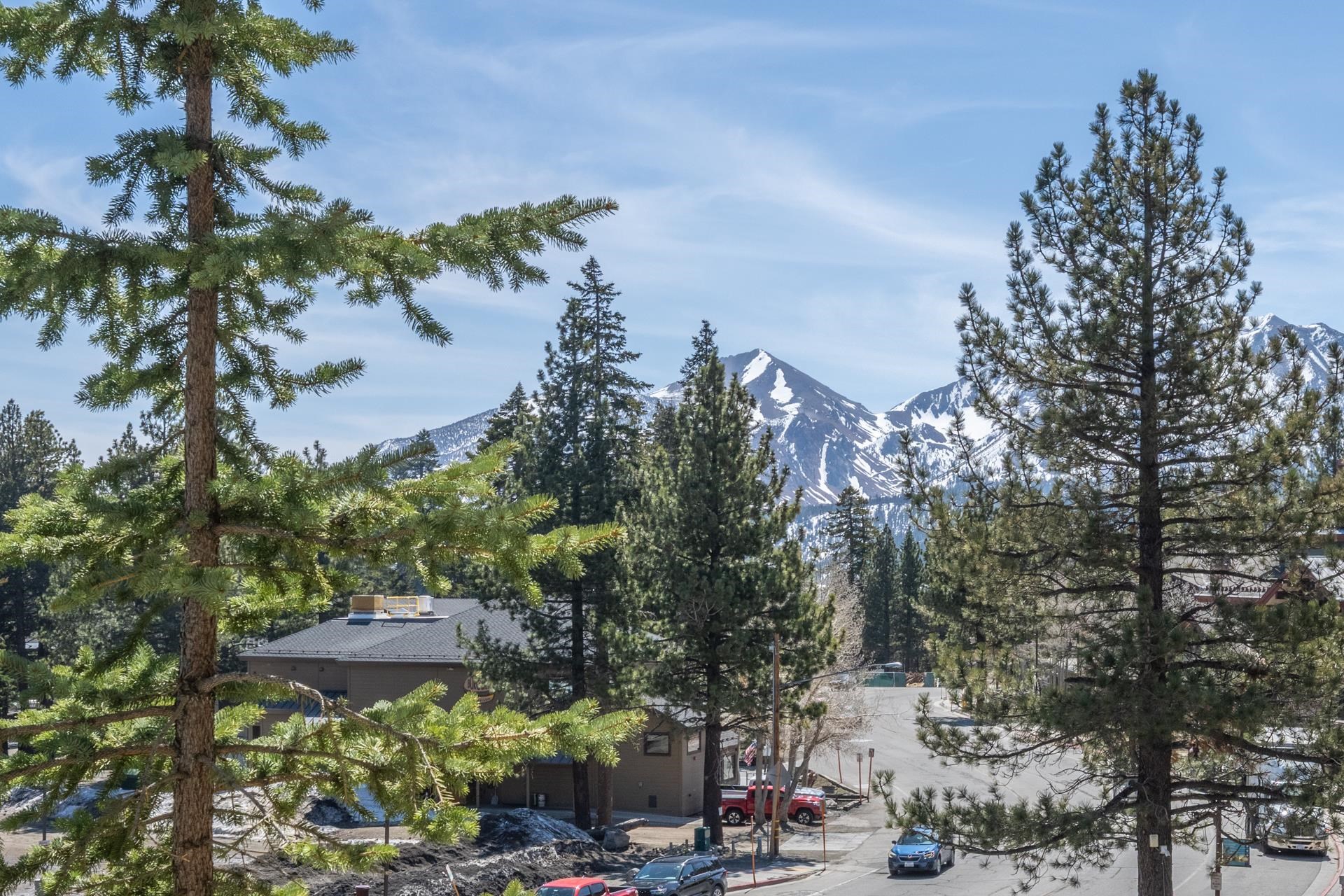 6201 Minaret Road, Unit 2221 Mammoth Lakes, CA 93546 - Photo 26 of 32 Snow-capped mountains form a scenic backdrop to a tree-lined street with scattered buildings