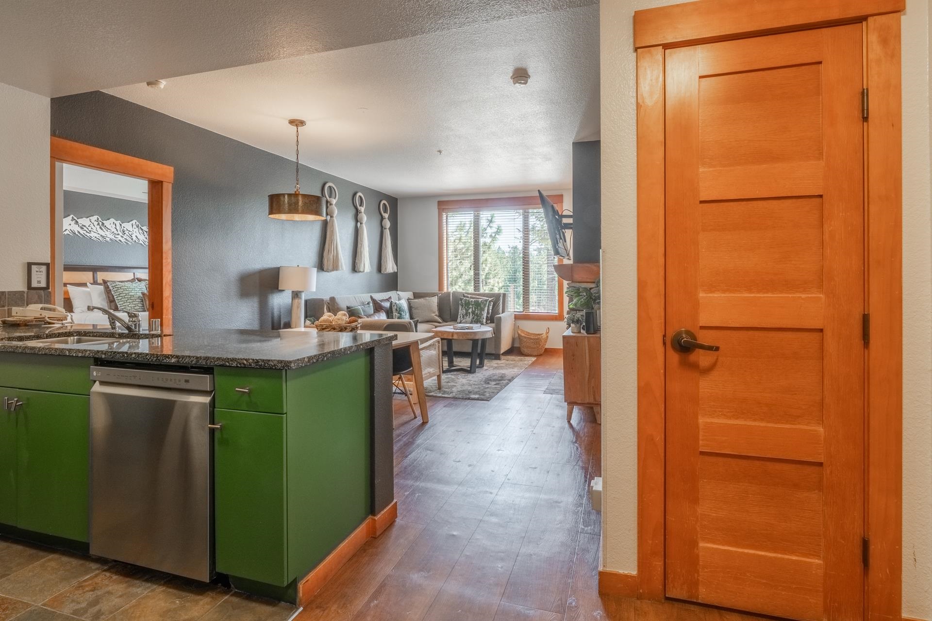 6201 Minaret Road, Unit 2221 Mammoth Lakes, CA 93546 - Photo 3 of 32 Open-concept living area featuring a kitchen peninsula with a stainless steel dishwasher, green cabinetry, and a dark stone-finish countertop
