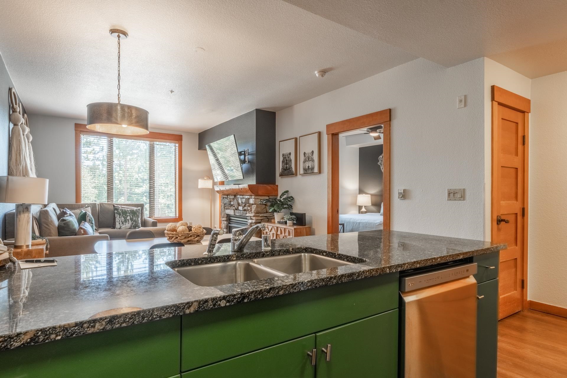 6201 Minaret Road, Unit 2221 Mammoth Lakes, CA 93546 - Photo 5 of 32 Kitchen island with a dual basin stainless steel sink and speckled countertop, green cabinetry, and an integrated stainless steel dishwasher
